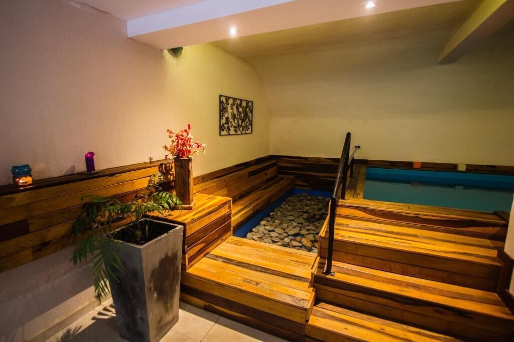 Et træværks spaområde med et boblebad, en lille pool og en trappe op til en højere etage.