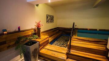 A wooden spa area with a hot tub, a small pool, and a staircase leading to a higher level.