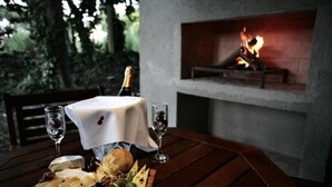 Una mesa de madera con una tabla de quesos, copas y una botella de champán. Se ve una chimenea al fondo.
