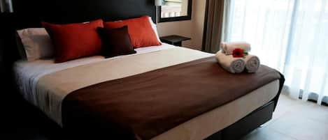 A neatly made bed with a brown bedspread, two red pillows, and a white pillow.