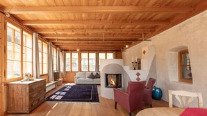 A spacious room with wooden floors, a fireplace, a sofa, and a dining table. - Romantic vacation apartment on a historic estate (Platzers)