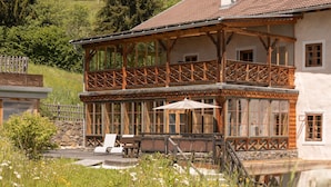 A two-story chalet with a balcony, wooden deck, and outdoor seating area. - Romantic vacation apartment on a historic estate (Platzers)