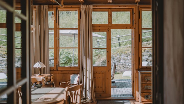 A wooden interior with a dining area, a table with chairs, and a view of the outdoors through large windows. - Romantic vacation apartment on a historic estate (Platzers)