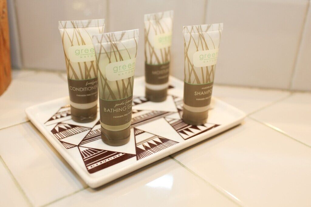 Four green bath products on a white tray with geometric patterns.