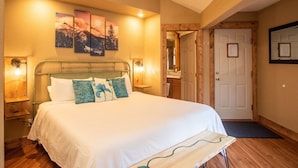 A bedroom with a bed, bedside lamps, a door, and a wall-mounted artwork. - Mt. Harvard Chalet at Creekside chalets (Salida)