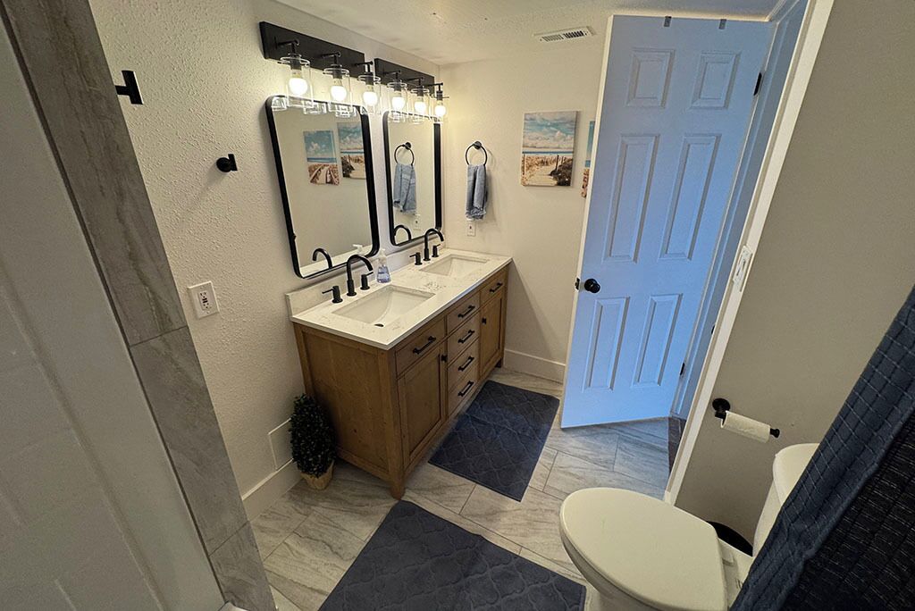 A bathroom with two sinks, a mirror, and a toilet.