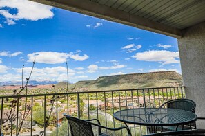 Enjoy breathtaking views of the surrounding mountains from this balcony, featuring a table and chairs.