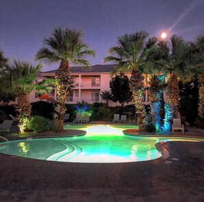 Ein Pool mit Palmen und einem Gebäude im Hintergrund.