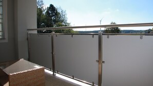 A balcony with a metal railing, a view of trees and wind turbines, and a clear sky. - Fichtelherz Herzerl (barrier-free) - 89 m² - 2 bedrooms - balcony - max. 5 pers. (Thierstein)