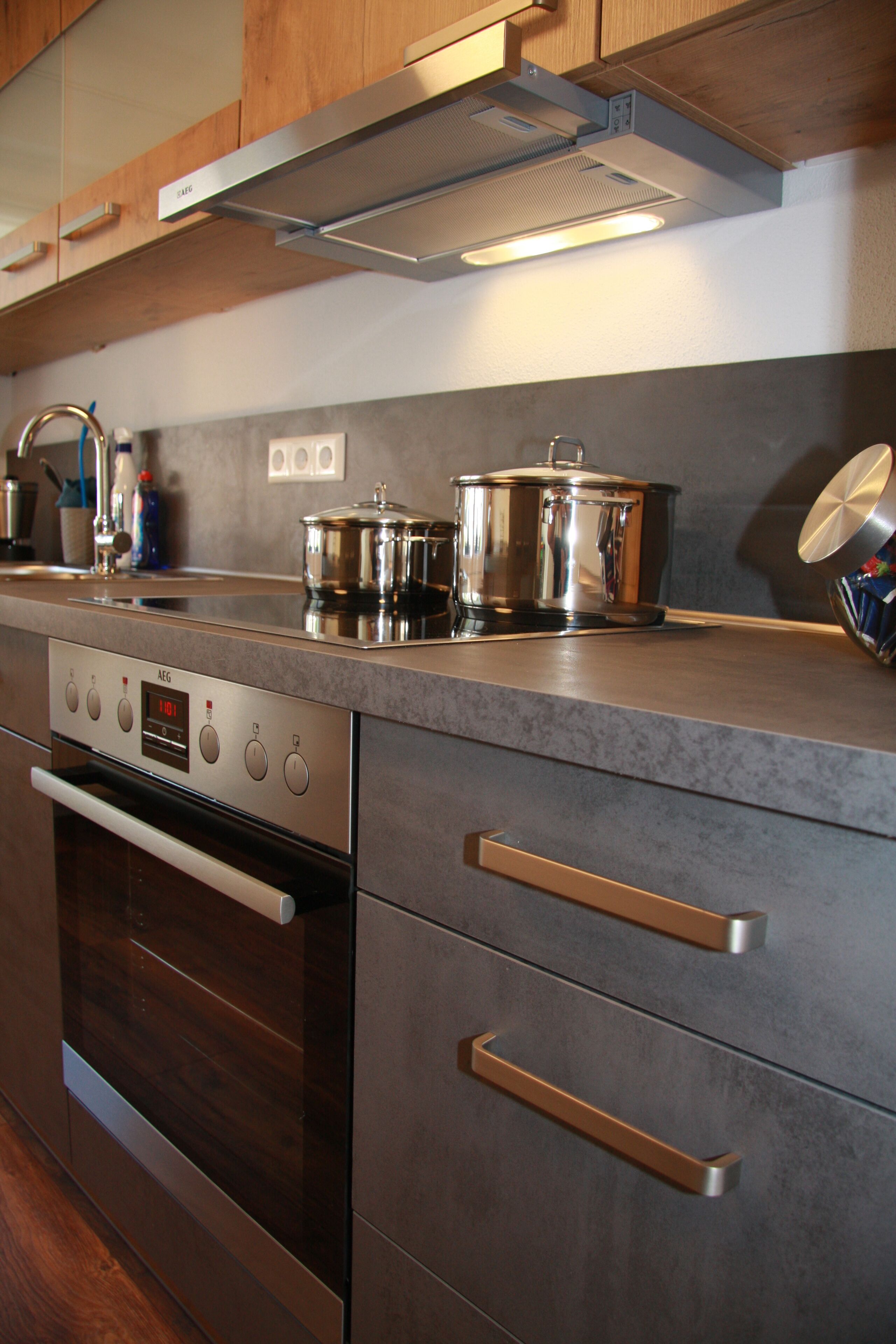 Une cuisine moderne dotée d’appareils électroménagers en acier inoxydable, de meubles en bois et d’un plan de travail gris.