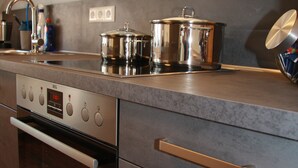 A modern kitchen with stainless steel appliances, wooden cabinets, and a grey countertop. - Fichtelherz Herzerl (barrier-free) - 89 m² - 2 bedrooms - balcony - max. 5 pers. (Thierstein)