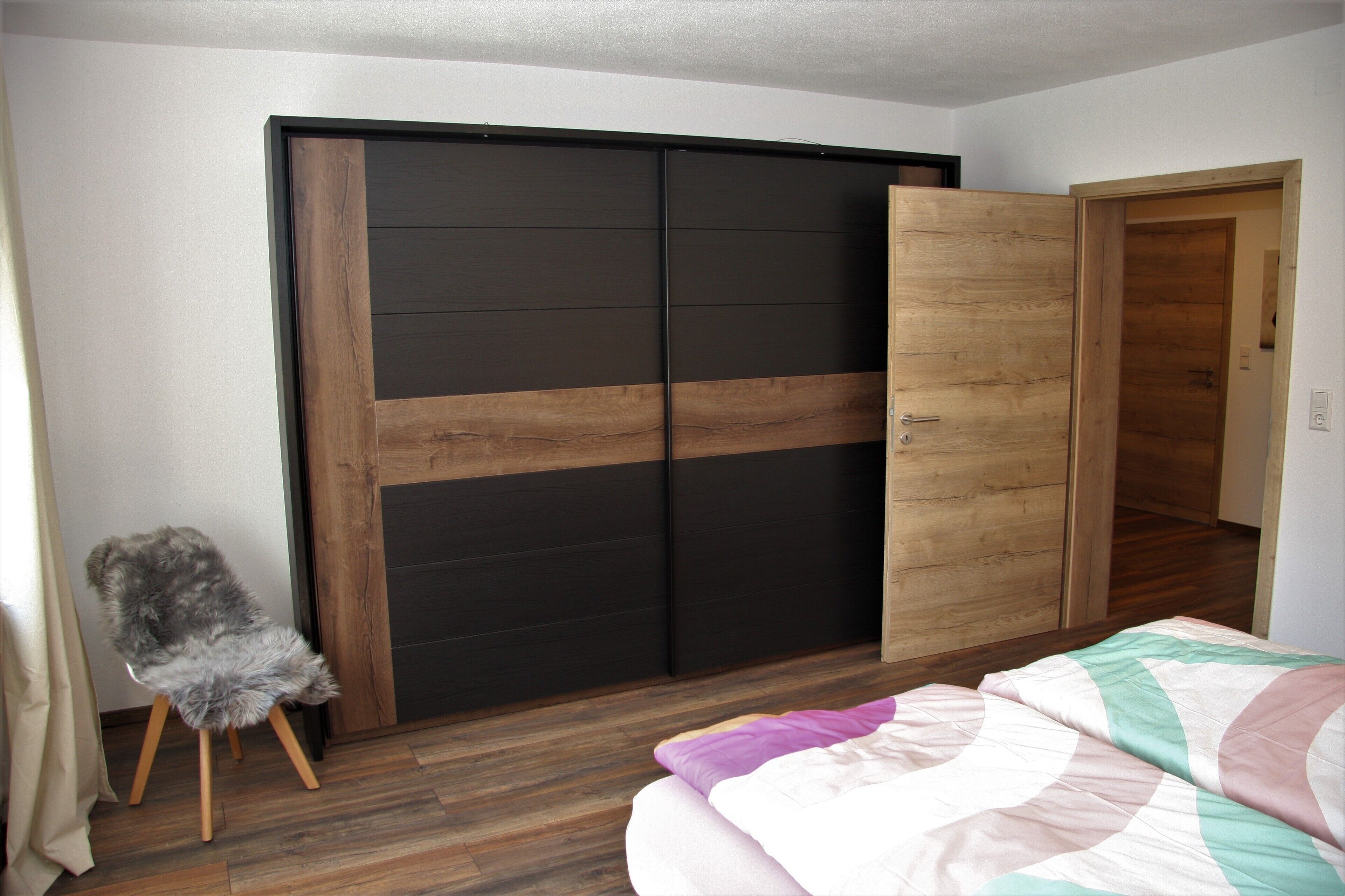 Une chambre à coucher avec un lit, une armoire en bois et une chaise.