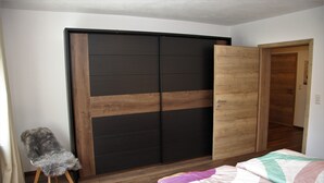A bedroom with a bed, a wooden wardrobe, and a chair. - Fichtelherz Herzerl (barrier-free) - 89 m² - 2 bedrooms - balcony - max. 5 pers. (Thierstein)