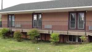 A two-story building with a balcony and a small garden area in front. - Caronoda Motel (Central City)