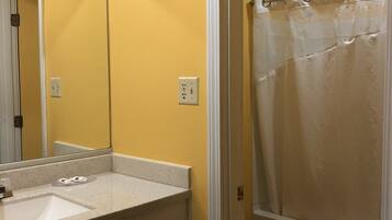 A bathroom with a yellow wall, a white sink, a mirror, and a shower curtain.
