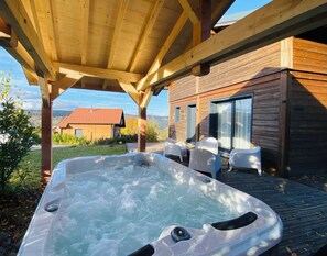 Une cabane en bois avec un jacuzzi et un espace salon extérieur.