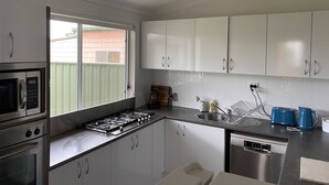 A modern kitchen with white cabinets, stainless steel appliances, and a window providing natural light.