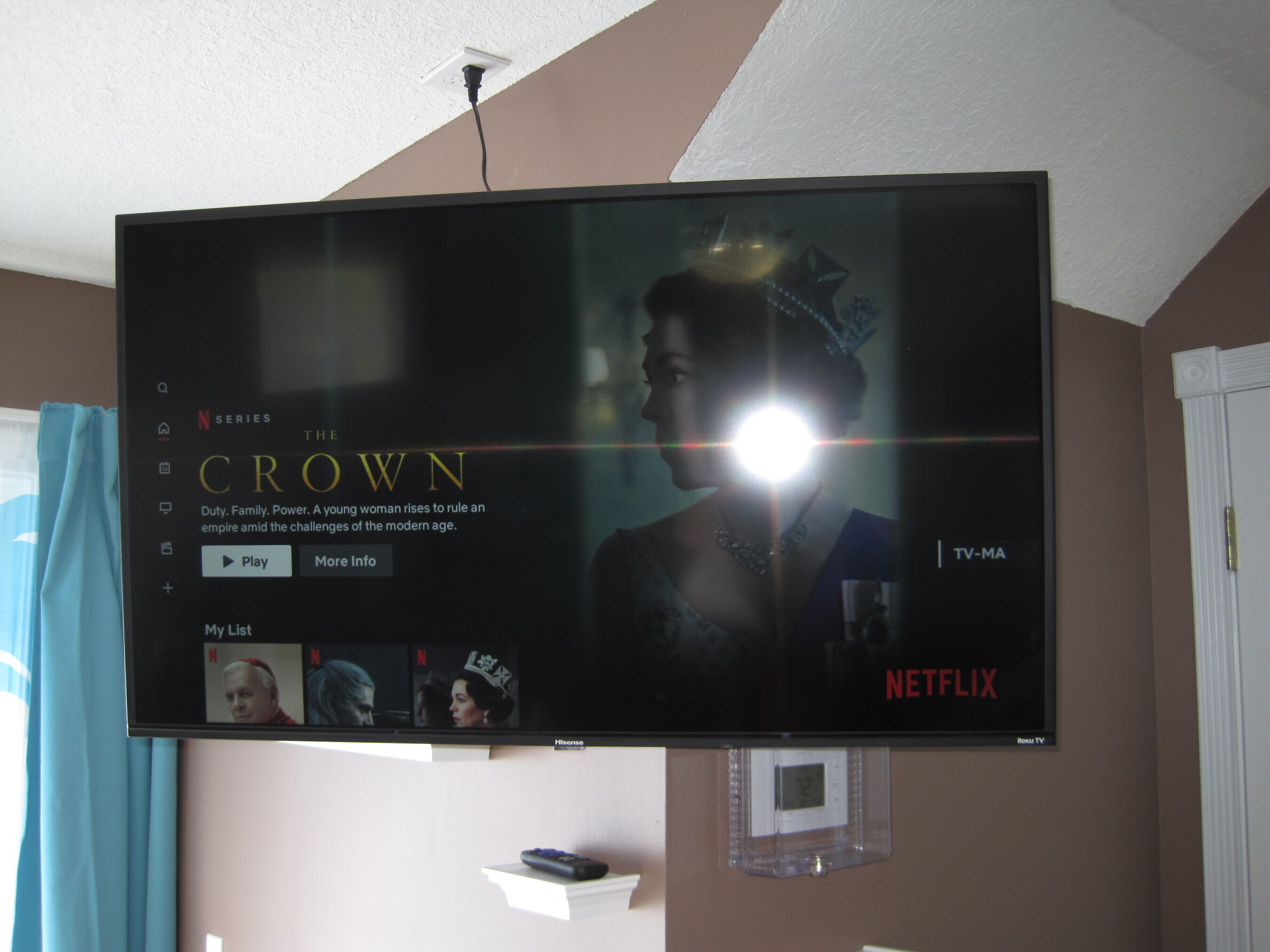 A flat-screen TV mounted on a wall displaying the Netflix series 'The Crown'.