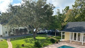 A backyard with a swimming pool, a covered patio, and a lawn with trees. - Mermaid relaxing studio with Pool (St. Augustine)