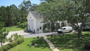 A white single-story house with a garage, surrounded by a well-maintained lawn and trees. - Mermaid relaxing studio with Pool (St. Augustine)