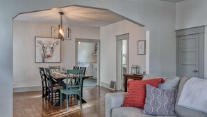 A modern living room with a dining area, wooden flooring, and a grey sofa with patterned cushions. - Circle Bar Manor — Spacious 4BR, Sheridan WY (Sheridan)
