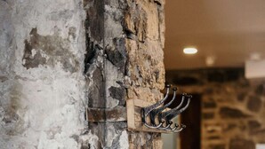 A rustic stone wall with a metal coat rack. - Modern Meets Rustic- 2 Bedroom in Old Quebec (Québec)