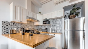 Een moderne keuken met witte kasten, een houten aanrecht, een roestvrijstalen koelkast en een decoratieve spatwand.
