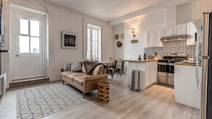 Een moderne keuken met witte kastjes, roestvrijstalen apparatuur en een decoratieve spatwand.