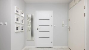 A hallway with a white door, a mirror, and framed pictures on the wall. - Seaside Apartment | 400 m to the Beach, Gym, Balcony (Kołobrzeg)
