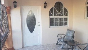 Una stanza con una porta bianca, una finestra con vetro decorativo e due sedie con coperture in plastica.
