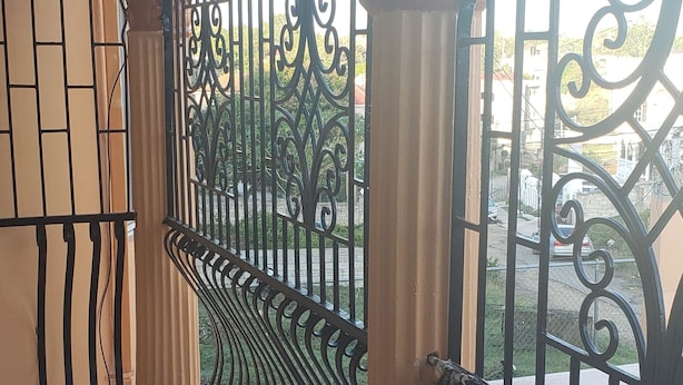 Un balcone con ringhiera in metallo, colonne e pavimento piastrellato.