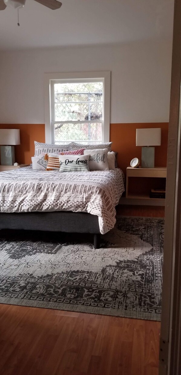 A bedroom with a bed, a window, a nightstand, and a lamp.