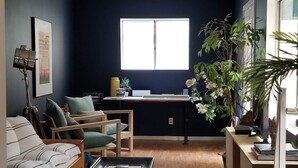 Una sala de estar con un sofá, sillas, una mesa de centro, un tapete, una ventana y una planta.