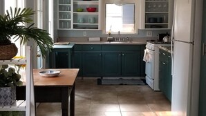 Una cocina con armarios azul turquesa, una mesa de madera y un refrigerador.