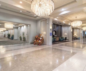 A spacious lobby with chandeliers, a reception desk, and seating areas.