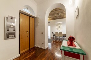 A hallway with wooden flooring, a wooden door, and a red and white table with a decorative object on top.
