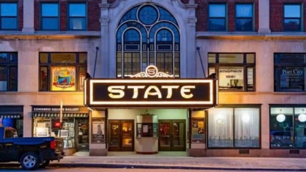 Ein Theater mit einer Marquee, auf der 'STATE' steht, und einem klassisch gestalteten Bau.