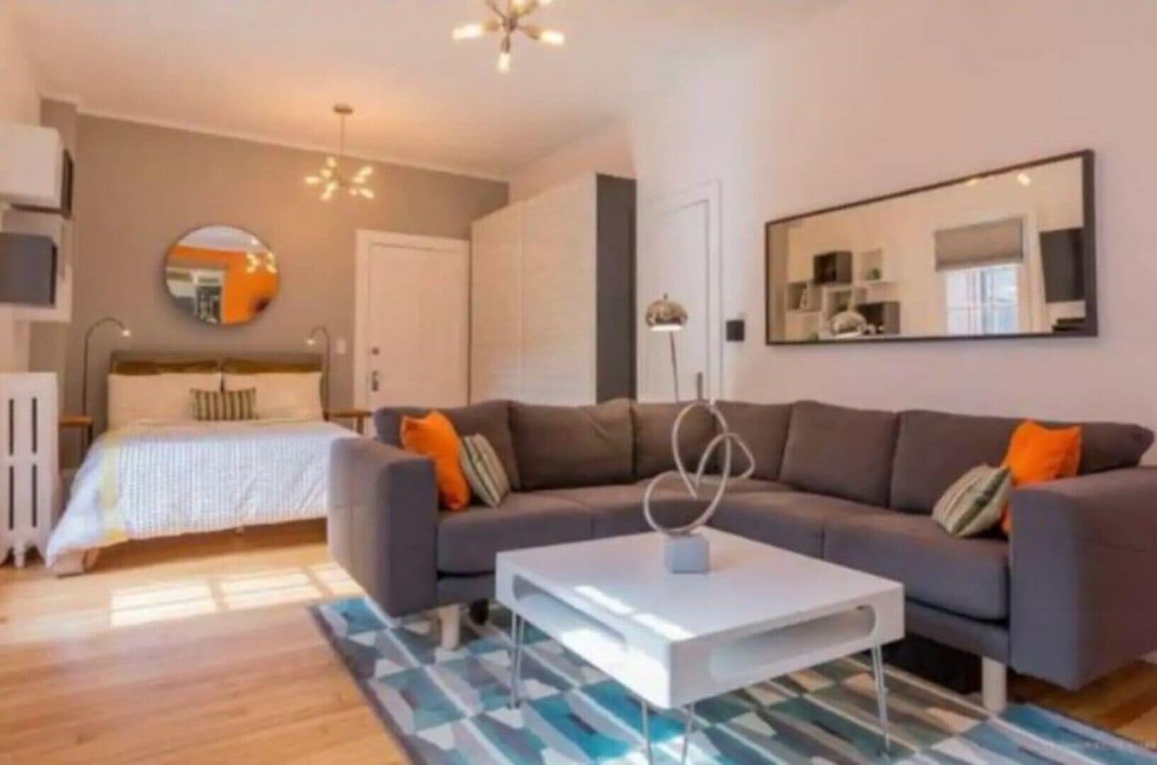 A modern living room with a grey sofa, a white coffee table, and a patterned rug.