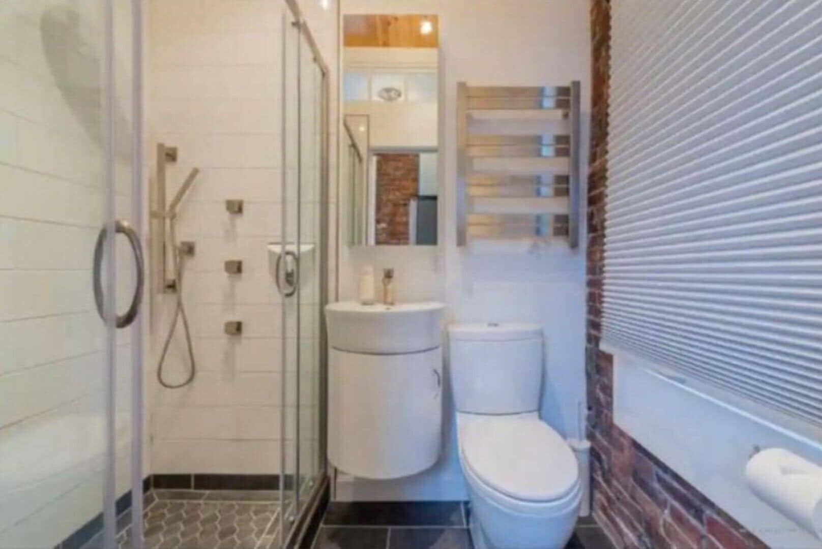 A bathroom with a glass shower enclosure, a toilet, and a sink.