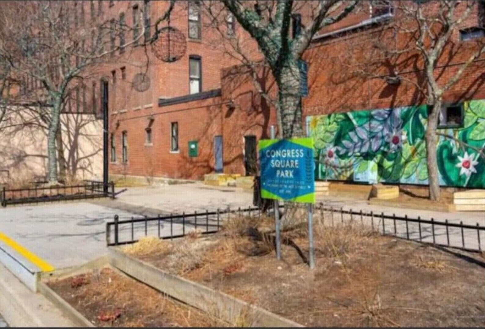 Ein Schild für den Congress Square Park, im Hintergrund eine Wandmalerei.