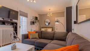 Ein modernes Wohnzimmer mit einer Eckcouch, einem weißen Couchtisch und einer Stehlampe.
