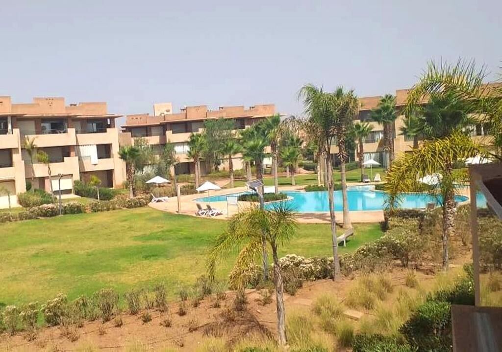 A hotel with multiple floors, a swimming pool, and palm trees.