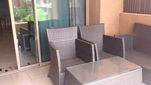 Un espace patio aménagé avec des meubles en osier et une porte vitrée donnant accès à un espace intérieur.