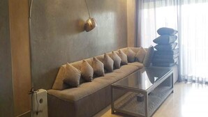 Un salon moderne avec un canapé, une table basse en verre et une lampe fixée au mur.