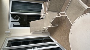 A room with a large window, a sliding door, and a small balcony area with a chair. - Wonderful Sanibel Island condo. 2 bed 2 bath. Sleeps 6. Weekly rental.  (Sanibel)