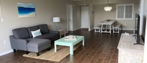 A living room with a grey sofa, a light blue coffee table, and a wooden floor.