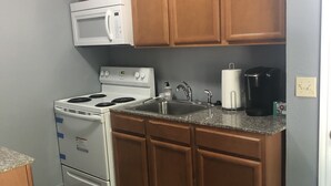 Una cocina con armarios de madera, estufa blanca, microondas, lavaplatos y cafetera.
