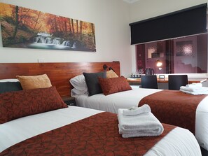 Une chambre d’hôtel avec deux lits, une tête de lit en bois, un tableau représentant une cascade et une vue sur un espace spa.