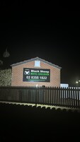 Un edificio de ladrillo con un cartel publicando 'Black Sheep Motel Goulburn' e información de contacto.