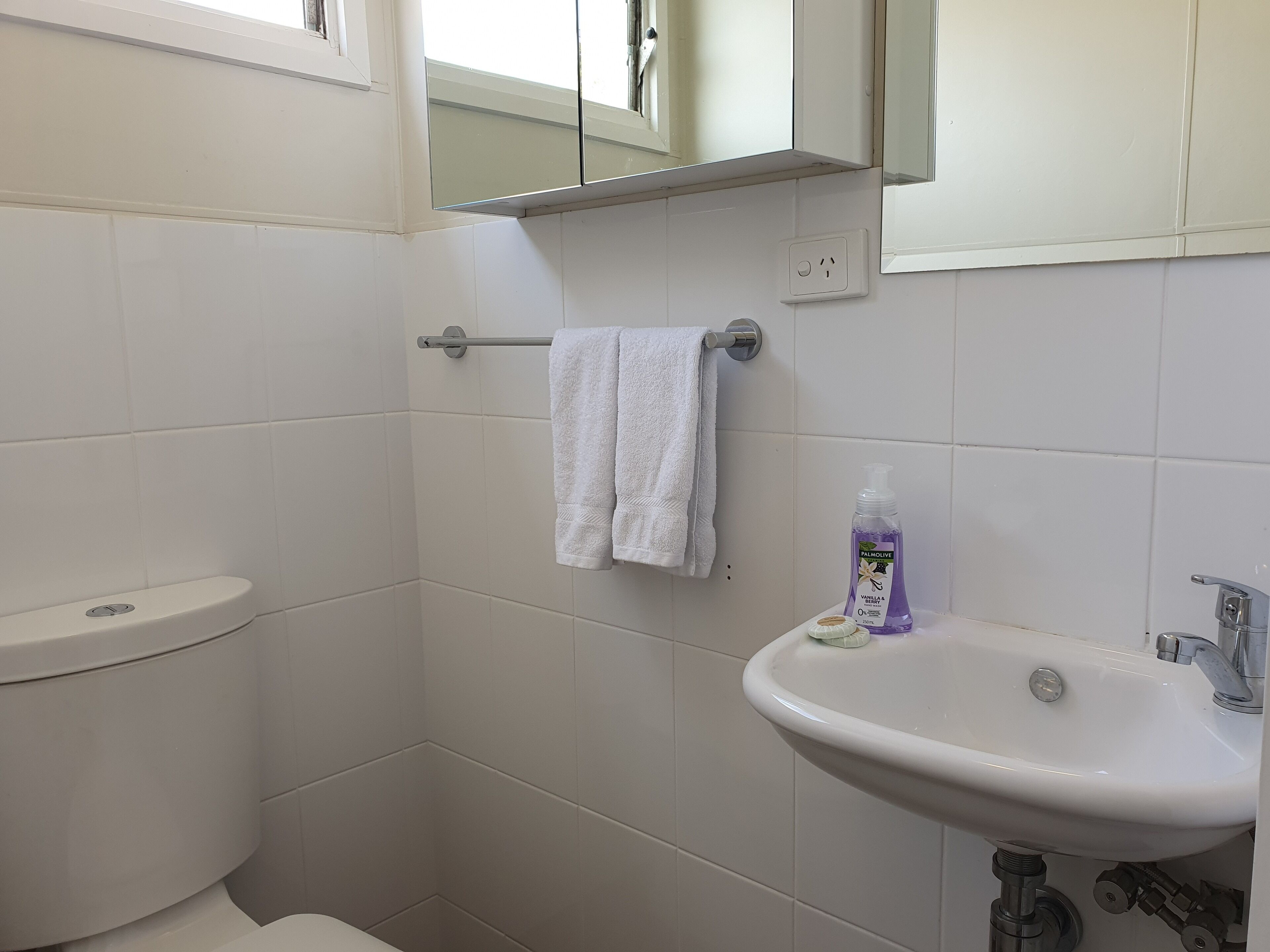 A bathroom with a toilet, a sink, and a towel rack.